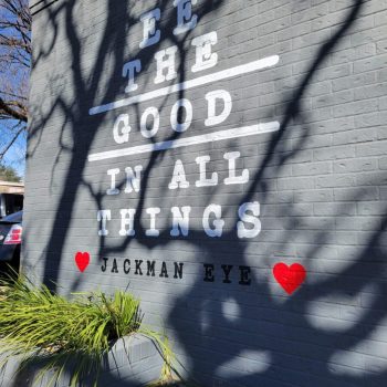 See The Good In All Things in white letters painted on a gray brick building.